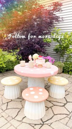 a pink table with yellow and white polka dots on it, surrounded by flowers in the background