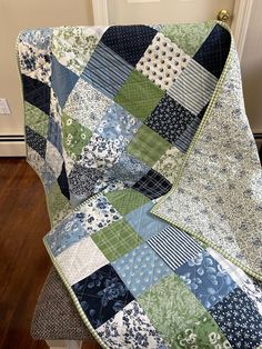 a blue and green patchwork quilt sitting on top of a wooden floor next to a door