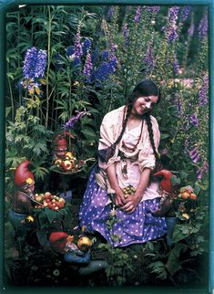 a woman sitting in a garden surrounded by flowers