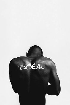 a man with the word ocean written on his back in white ink against a black and white background