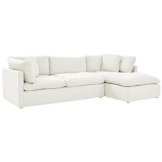 a white sectional couch with pillows on the top and bottom corner, facing away from the camera