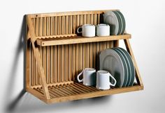 a wooden shelf with plates and cups on it next to a wall mounted dish rack
