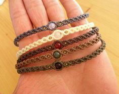 a hand holding four different bracelets on it's palm, with beads in the middle