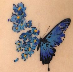 a blue butterfly sitting on top of a white surface next to some small blue flowers