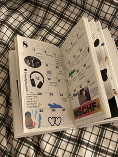 an open book with stickers on it sitting on top of a plaid cloth covered bed