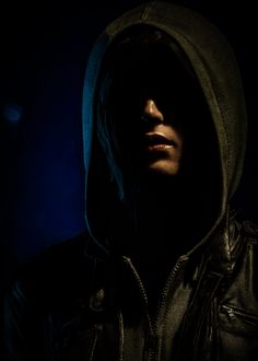 a man wearing a hooded jacket in the dark