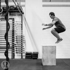 a man jumping over a block in a gym