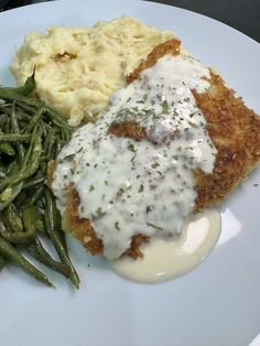 a white plate topped with meat, mashed potatoes and green beans