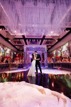 a bride and groom standing in the middle of a dance floor with chandeliers hanging from the ceiling