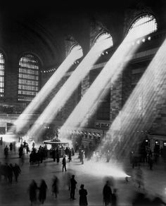 several beams of light are shining in the middle of a train station as people walk by