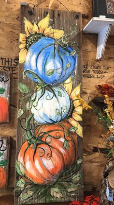 some pumpkins and sunflowers are painted on wood