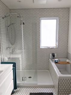 a white bathroom with black and white tile on the floor, shower stall, sink and bathtub