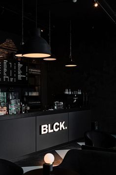a black bar with lights hanging from it's ceiling and chairs in front of it