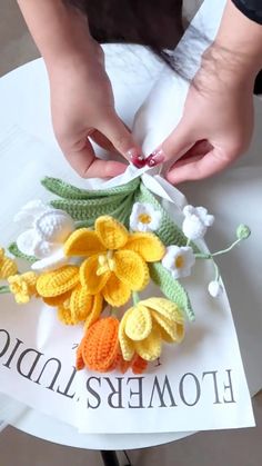 a woman is making crocheted flowers out of yarn and cotton on top of a sign