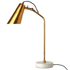 a gold and white lamp with a black cord on the end, sitting in front of a