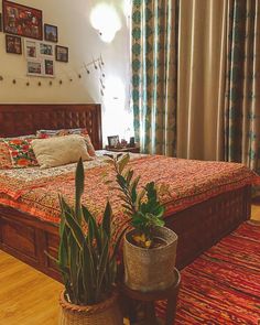 a bed room with a neatly made bed and two potted plants