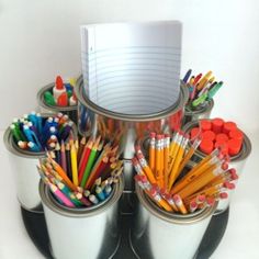 there are many pencils and markers in the cups