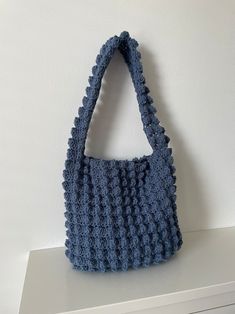 a crocheted blue purse sitting on top of a white shelf