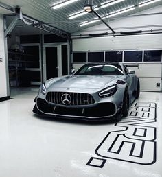 a mercedes sports car is parked in a garage with black and white lines on the floor