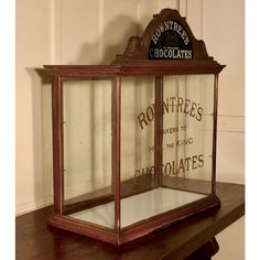 an old fashioned glass box on top of a wooden table in front of a white wall