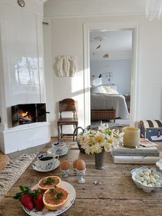 a wooden table topped with plates and bowls filled with food next to a fire place