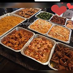 many trays of food are arranged on a table with the words i love seafood kitchen