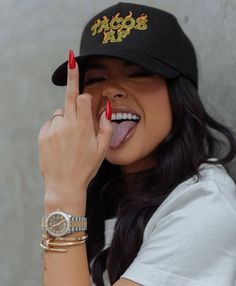 a woman wearing a hat and holding her finger up to her face while making a peace sign