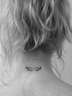 a woman's back neck with a small angel wing tattoo on her left side