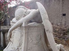 an angel statue sitting on top of a cement planter