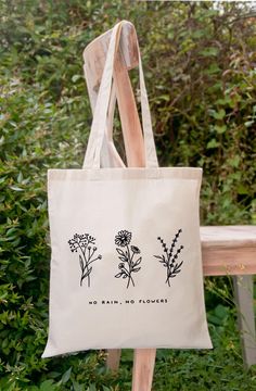 a white tote bag with three flowers on it and the words no rain, no flowers