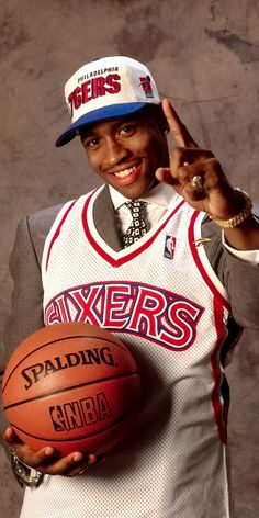 a man holding a basketball and giving the peace sign