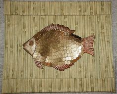 a fish made out of coins sitting on top of a bamboo mat