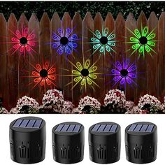 four solar powered flower lights in front of a wooden fence with flowers on the side