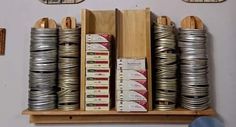 several stacks of books are stacked on a wooden shelf in front of two clock faces