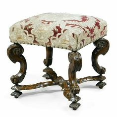 an ornately carved foot stool with a red and white upholstered fabric seat