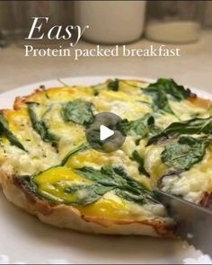 a pizza with spinach and cheese on it being cut by a chef's knife