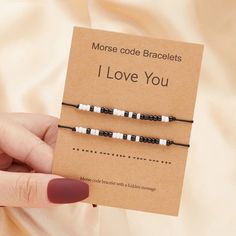 a woman holding two black and white beaded bracelets in front of a card that says i love you