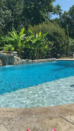 a person in pink flip flops standing next to a swimming pool with water running down it