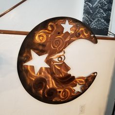 a metal moon and star hanging on the side of a wall next to a dvd rack