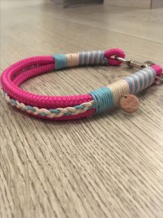 a pink, blue and white rope bracelet with a wooden disc charm on the clasp