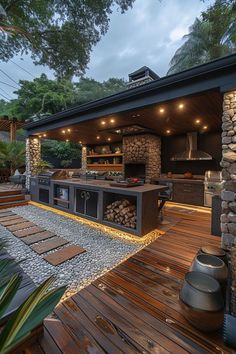 an outdoor kitchen with wood flooring next to a stone wall and grill area in the background