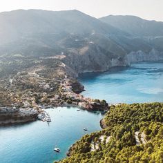 an aerial view of a bay with boats in the water and mountains in the background