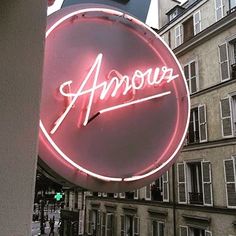 a neon sign that says amou on it's side in front of some buildings