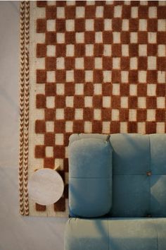 a blue couch sitting in front of a wall with a checkered design on it