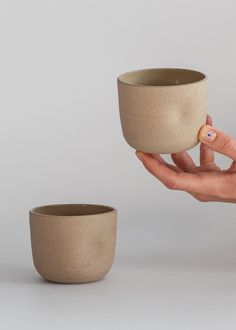 a hand holding a small cup in it's right hand and another one on the other side