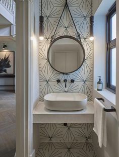 a white sink sitting under a round mirror next to a wall mounted faucet