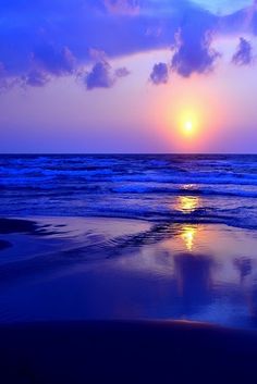 the sun is setting over the ocean with clouds in the sky and water reflecting on the sand