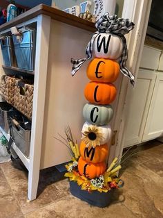 a stack of pumpkins sitting on top of a kitchen floor next to a counter