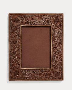 a brown leather frame with flowers and leaves