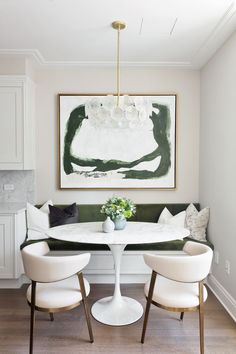 a dining room table with white chairs and a painting hanging on the wall above it